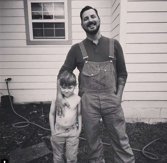 man stands with little boy in front of house
